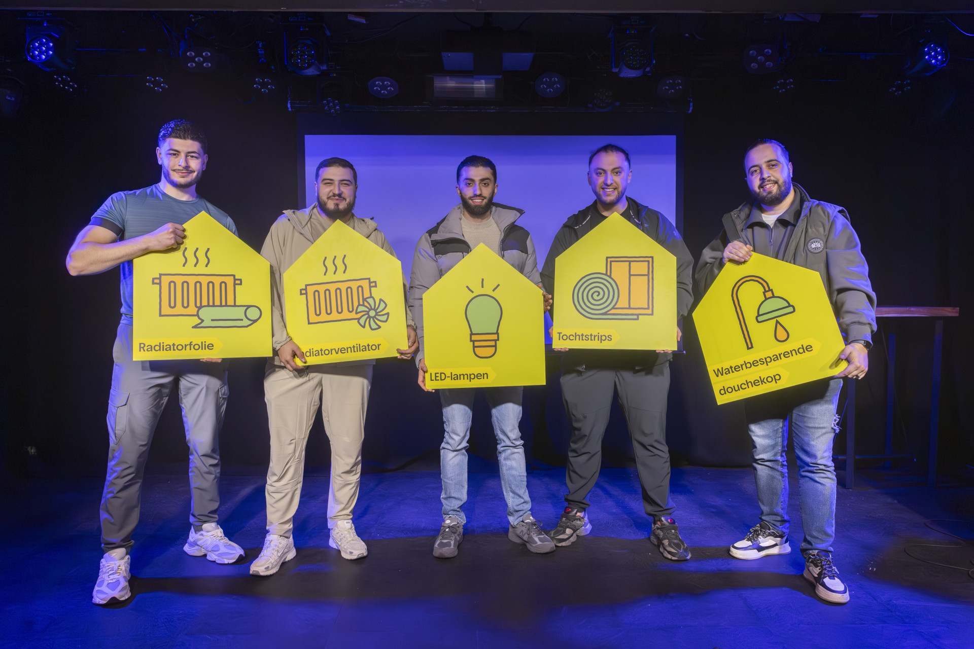 Vijf mannen poseren op een podium met gele borden in hun handen.