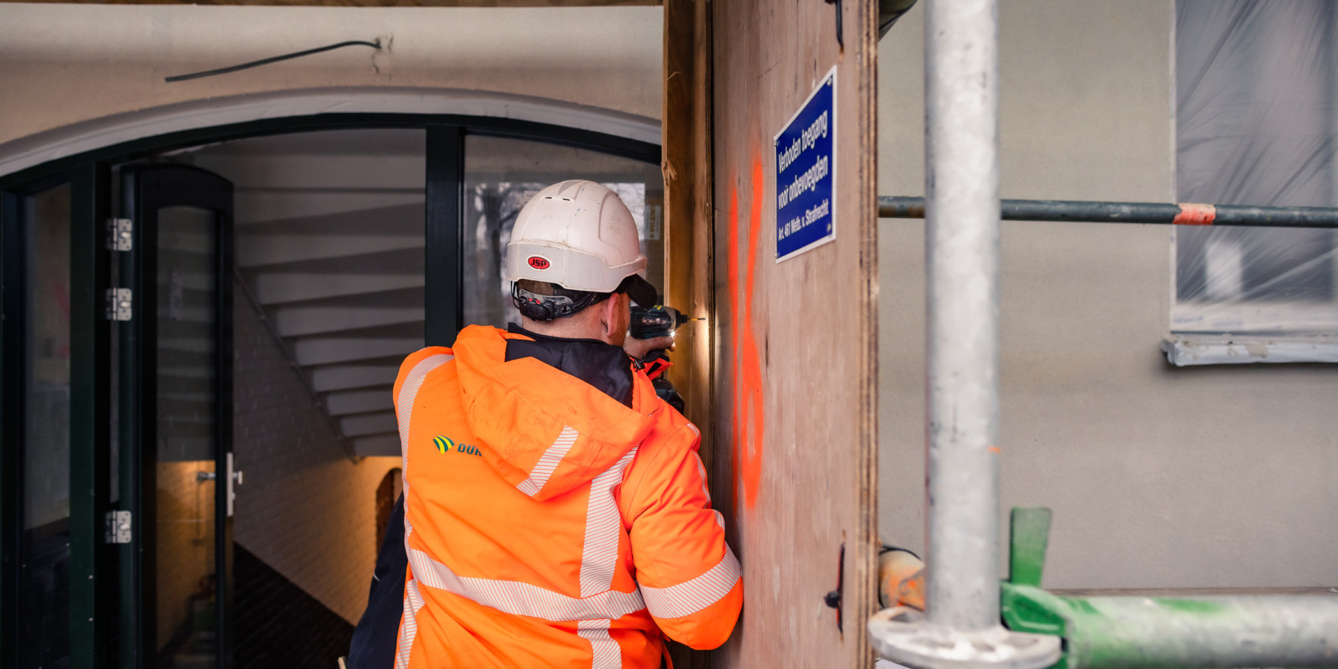 Bouwvakker in felgekleurd jack aan het werk.