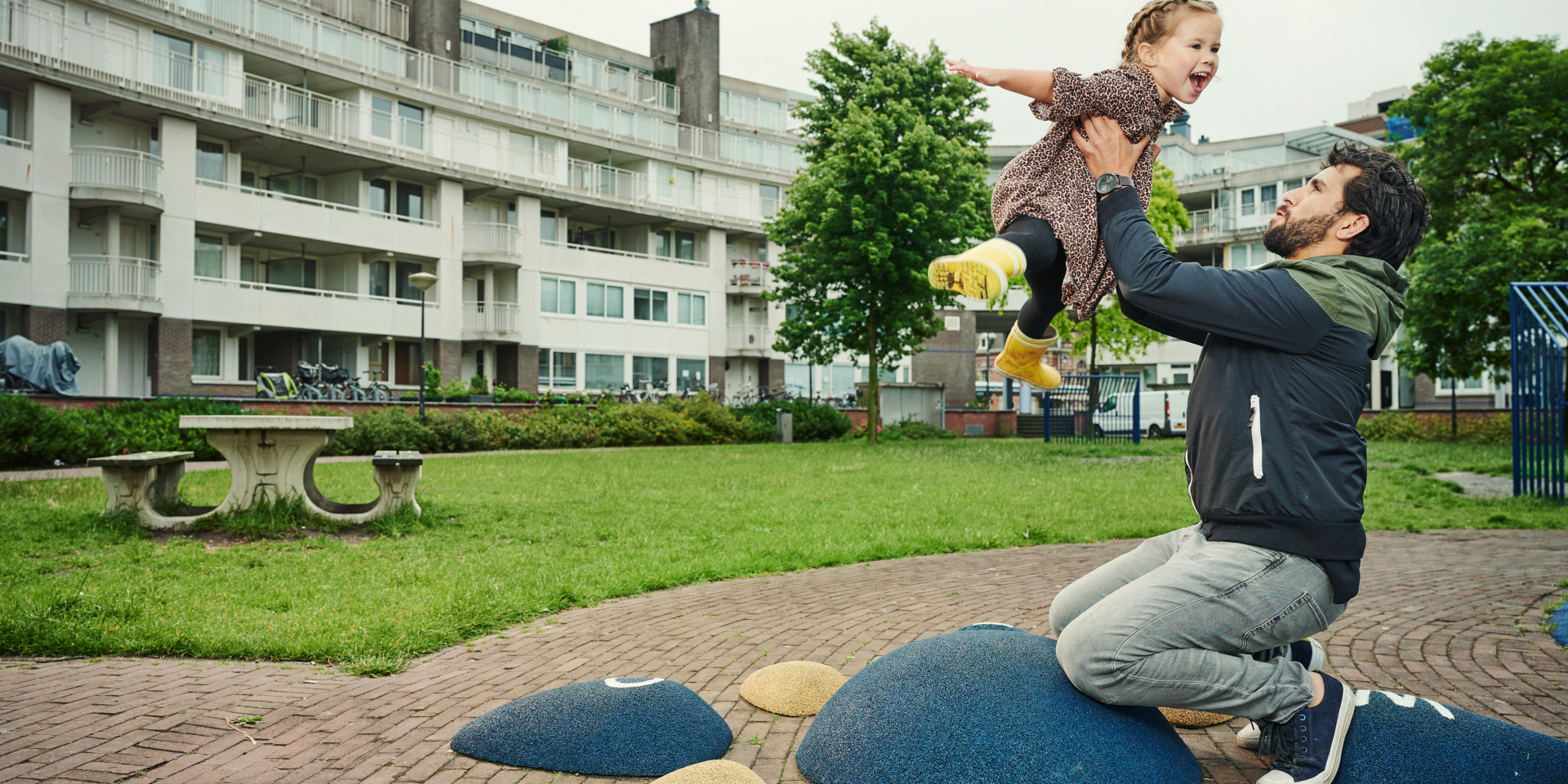 Vader en kind spelen samen in een buitenomgeving.